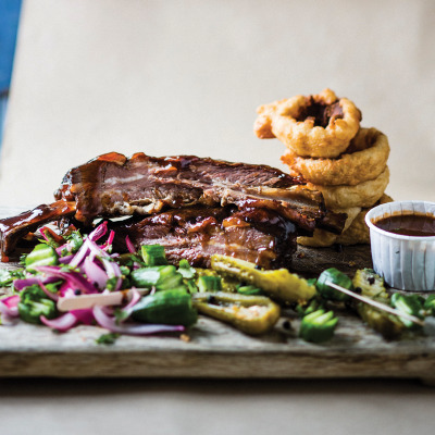 Smoked giant beef ribs with beer-battered onion rings and jalapeno pickle