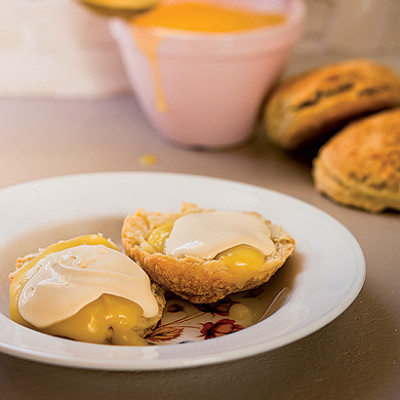 Golden scones topped with thick lemon curd and clotted cream