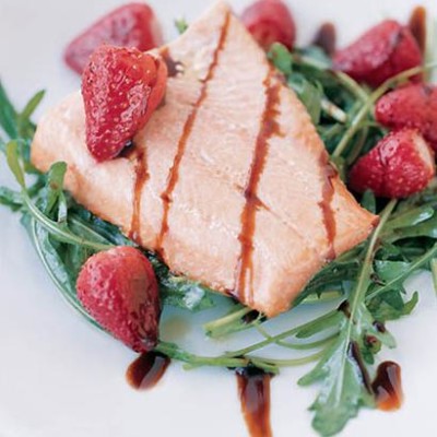 Grilled salmon trout and strawberries with balsamic on wild rocket