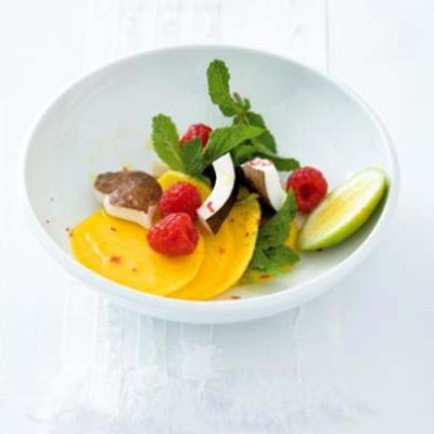 Mango, coconut and raspberry salad with pink peppercorns and mint leaves