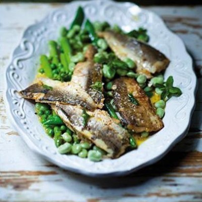 Panfried hake fillets on a bed of spring greens